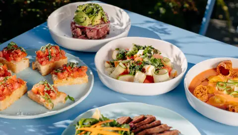 Un service de plats colorés sur la table bleue de la terrasse de Tonique
